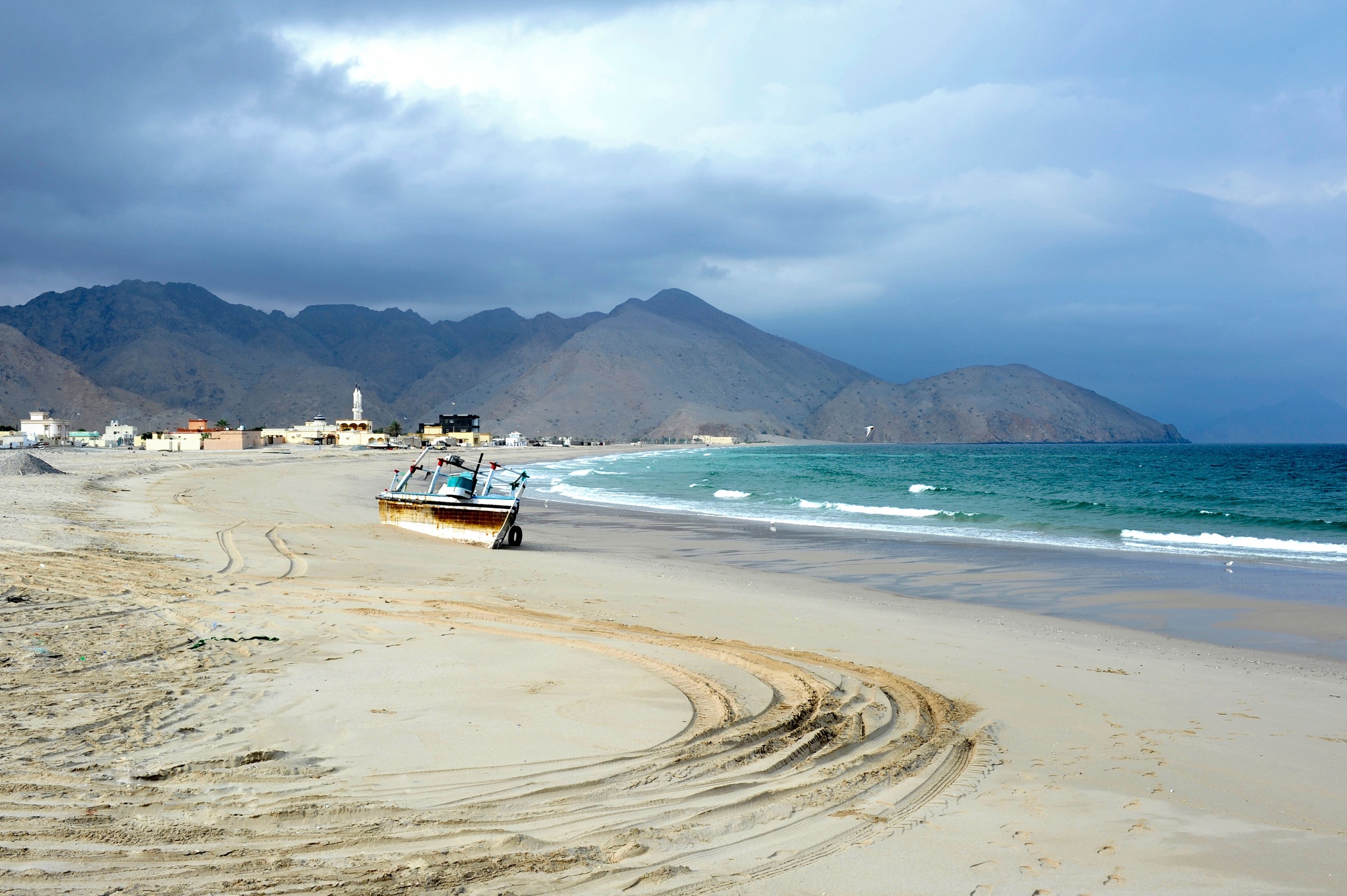 Fishing boat on an Omani beach beneath the Hajar Mountains